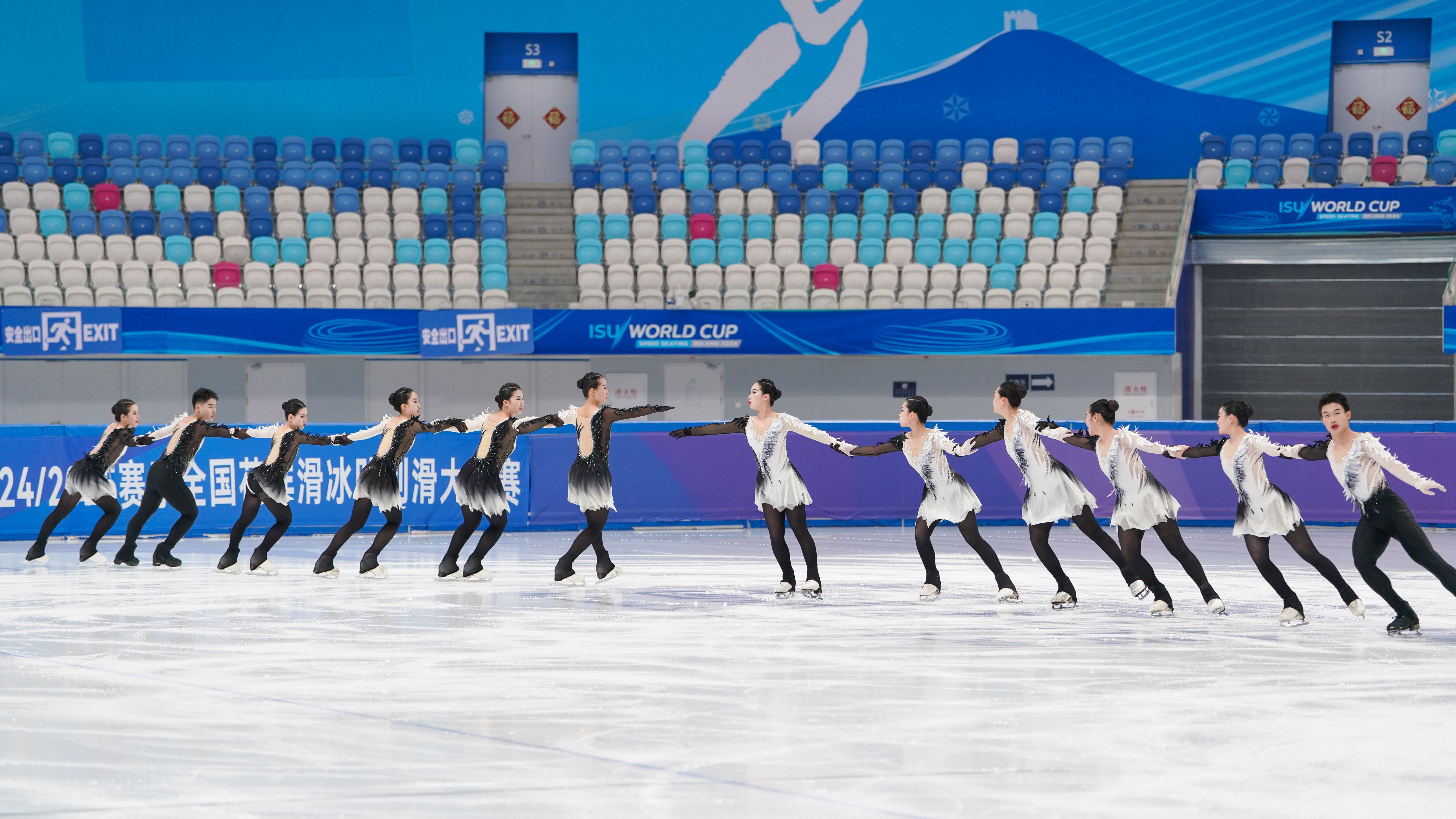 A team of figure skaters holding hands in a line across the ice